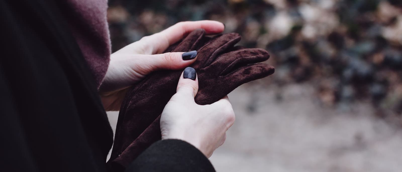 Close-up of hands adjusting warm winter gloves outdoors in flat daylight.