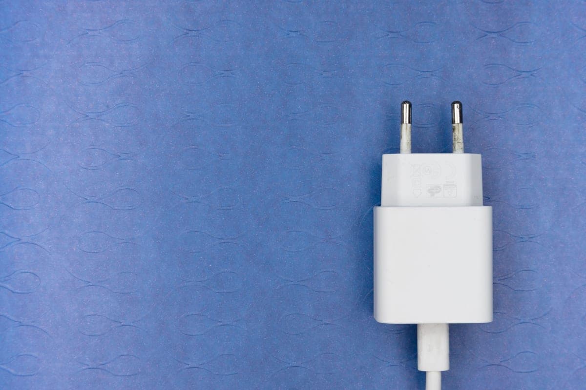A battery pack charging from a wall outlet beside a folded jacket, soft daylight.