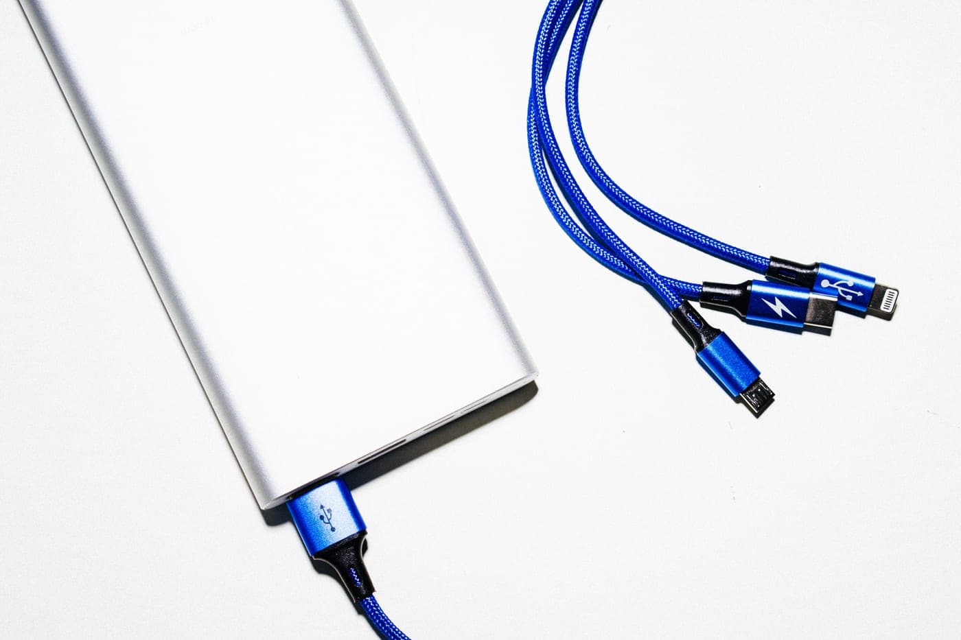 A small lithium power pack and cable on a pale surface in soft daylight, the kind that clips into a heated jacket pocket.