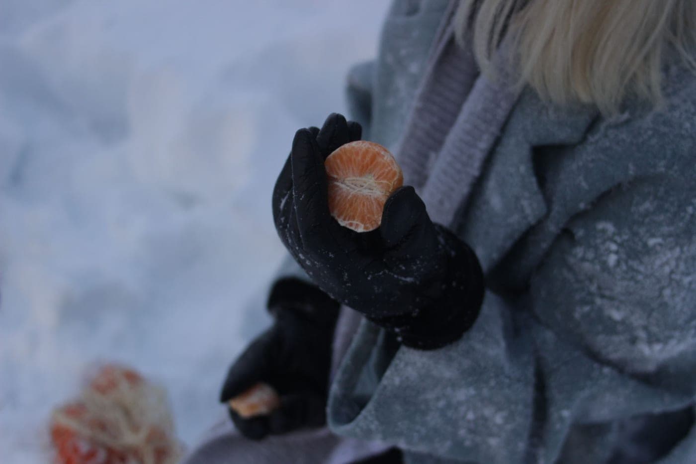 Bare hands on cold metal in flat winter daylight, frost on the surface, the everyday cold that drives people to heated gloves.