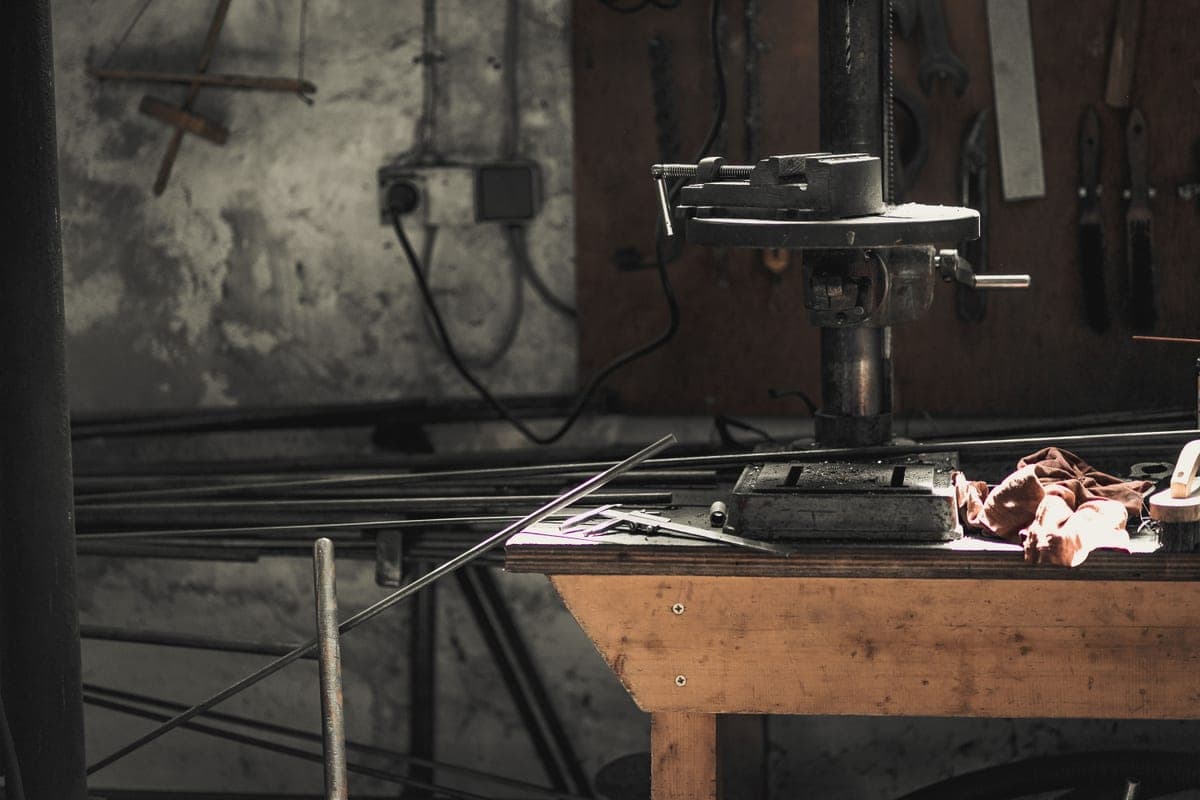 A heavy work jacket folded on a workbench beside a tool battery, flat daylight.
