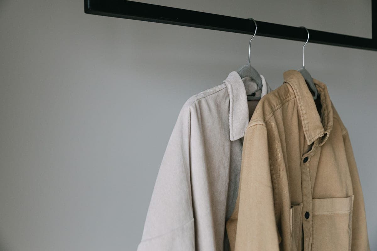 A quilted heated jacket on a hanger against a pale wall in soft, even light.