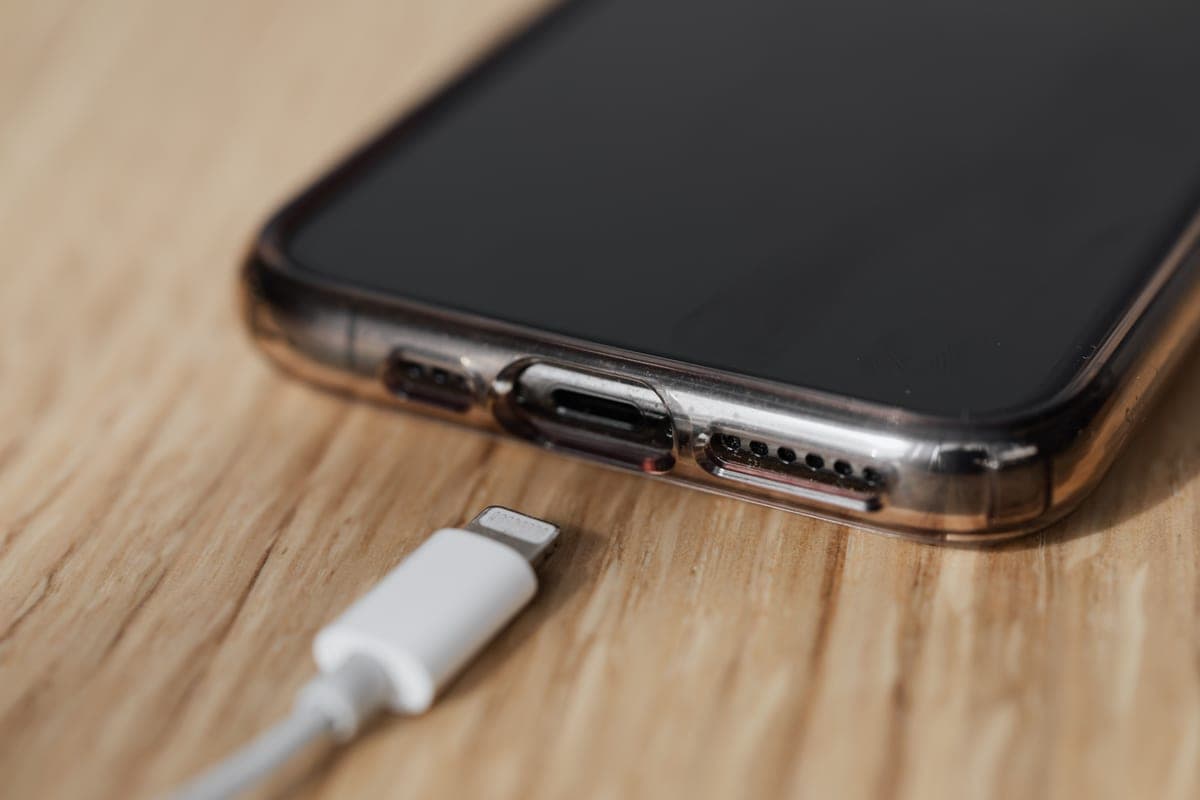 A charging cable and small battery pack on a pale desk in soft daylight.