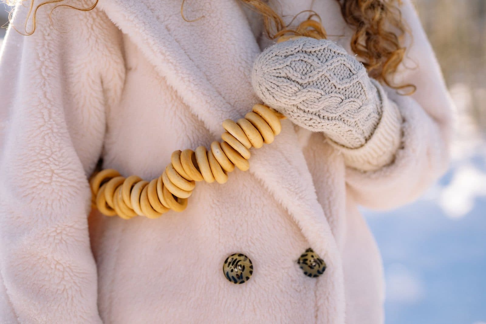 Cozy winter fashion featuring beige coat and knit mittens on a cold day.