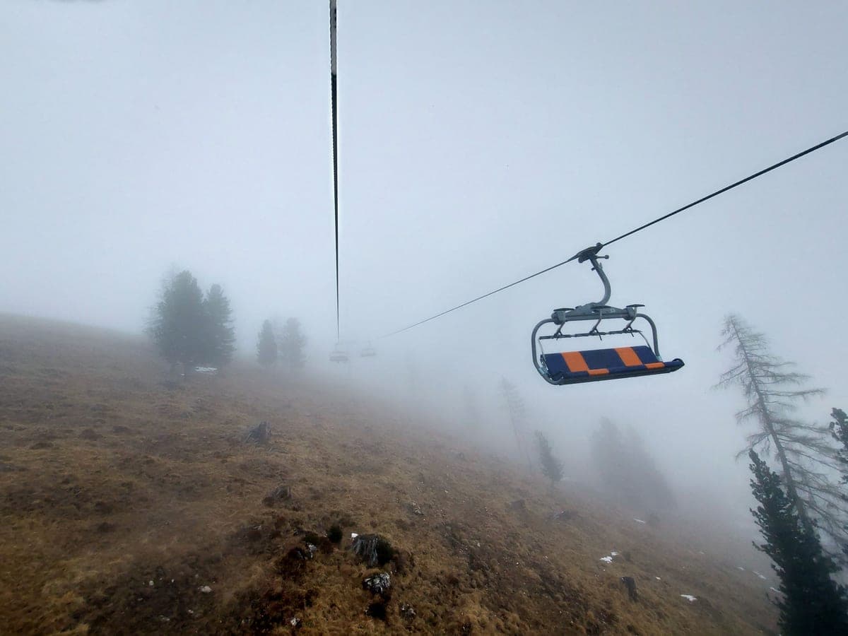 A chairlift line in flat overcast mountain light, pale snow and muted colors.