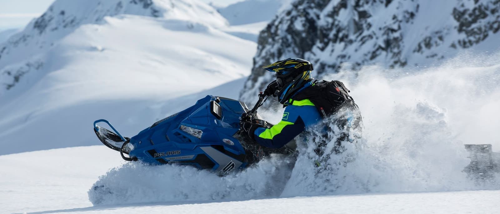A rider on a snowmobile crossing a bright snowy landscape in flat winter daylight.