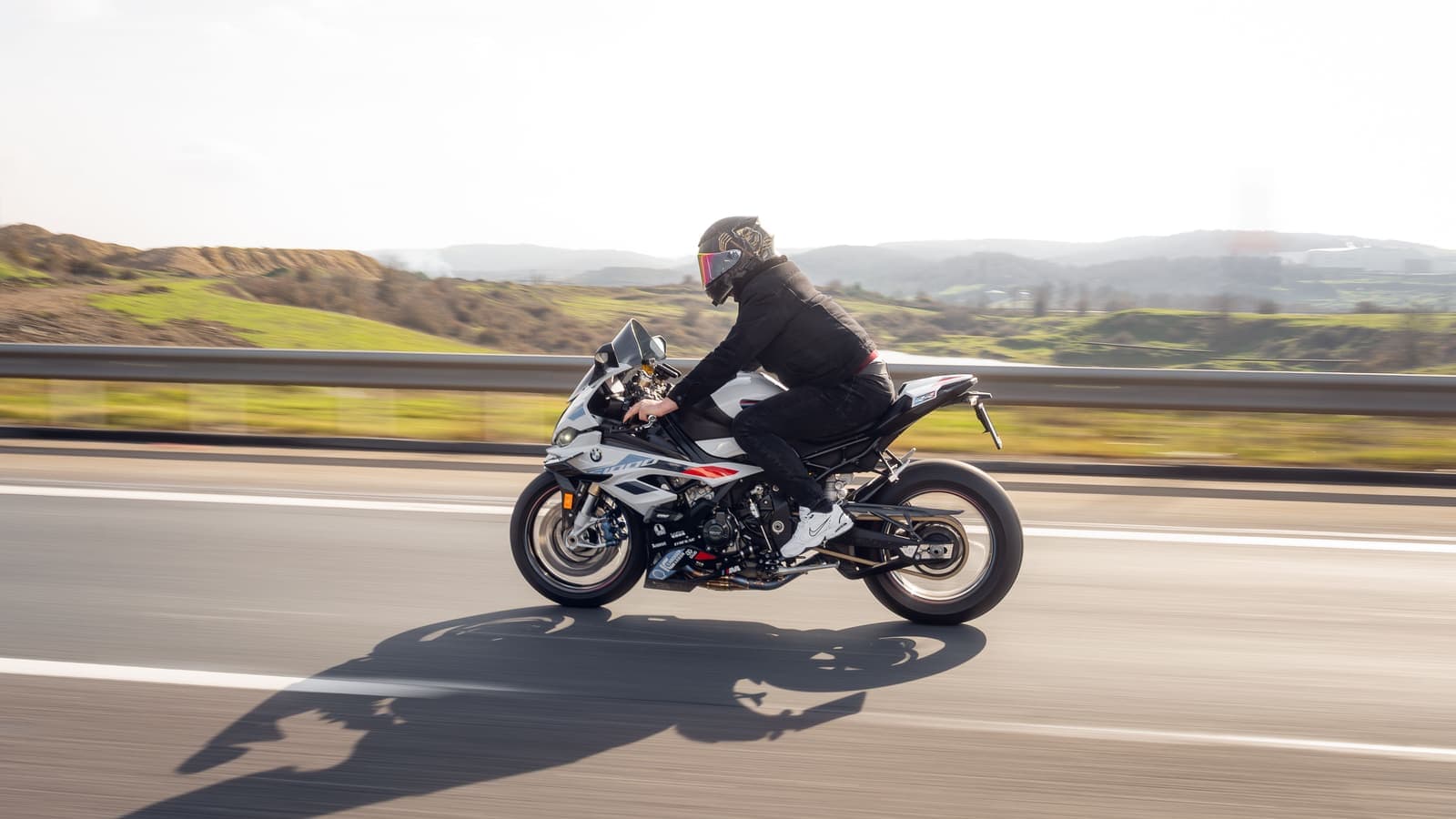A motorcyclist rides on an open highway during the day, showcasing speed and adventure.