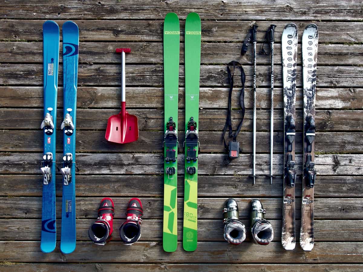 Ski boots and poles propped against a rail in flat, pale mountain daylight.