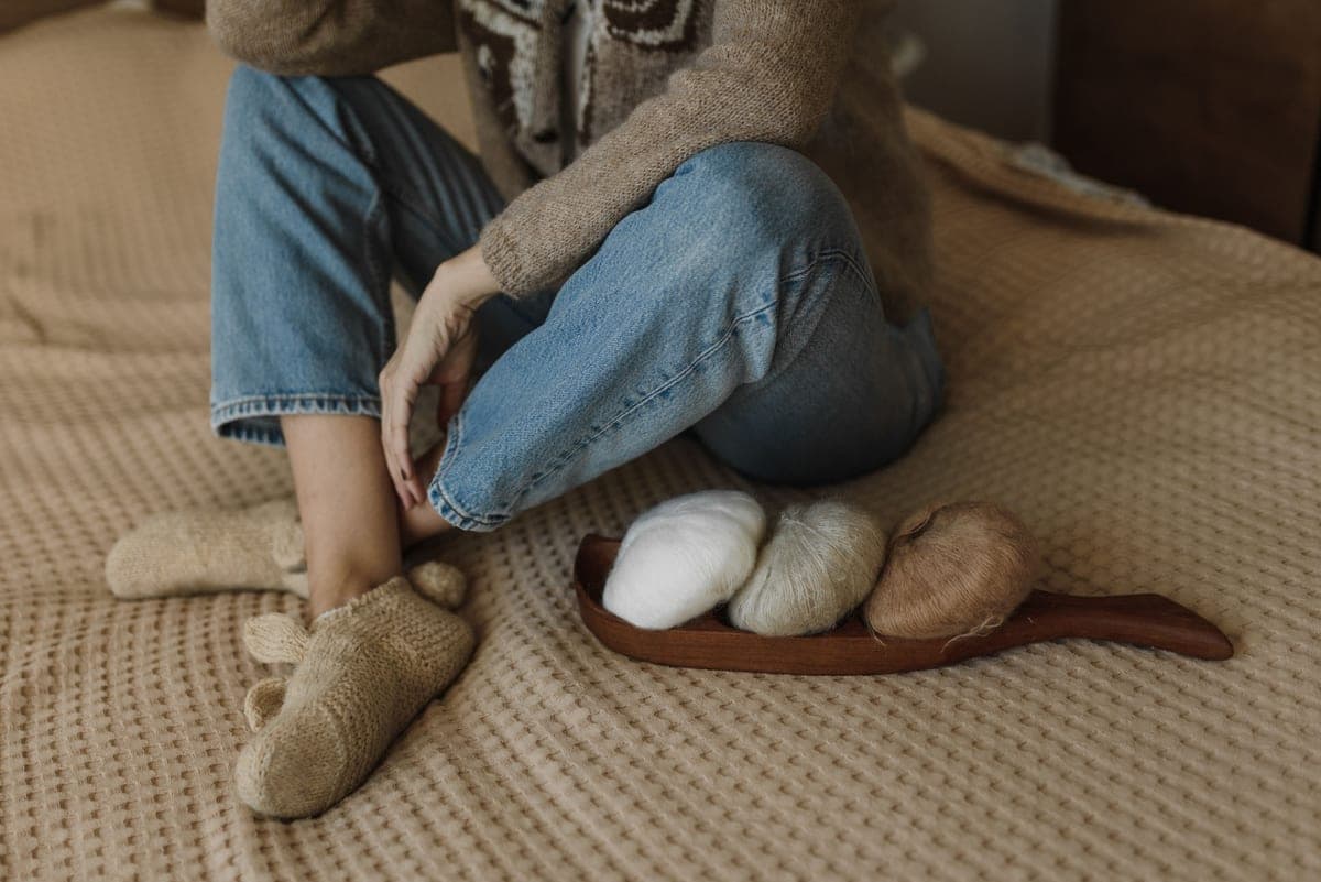 Soft knitted socks folded on a pale blanket in gentle indoor daylight.