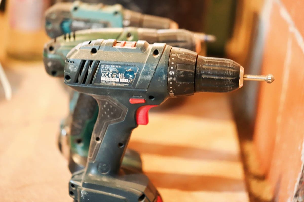 Cordless tool battery packs lined up on a workbench in flat, even daylight.